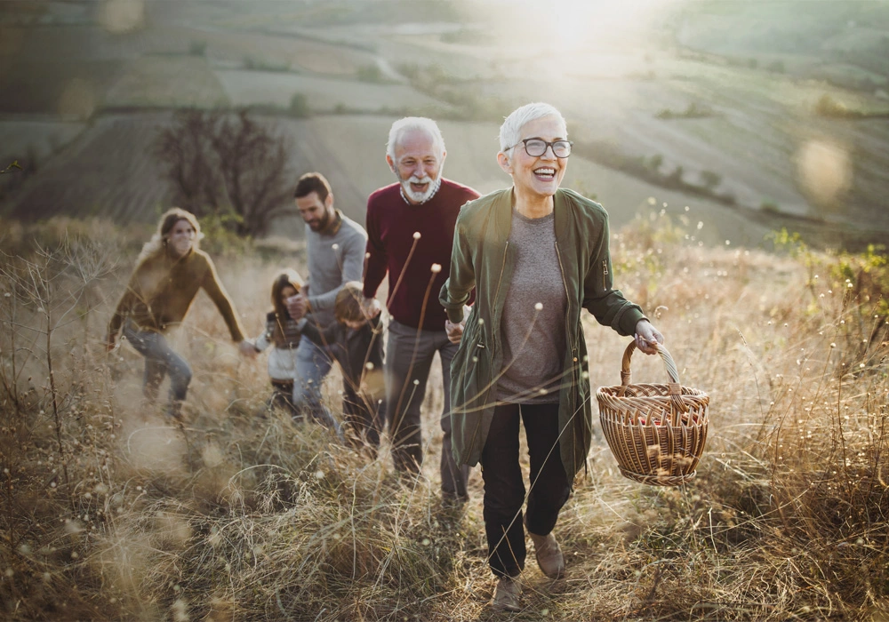 Uma família com dois idosos, mãe, pai e dois filhos a caminhar na natureza, de mãos dadas.