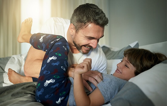 Pai brinca com o seu filho à hora de deitar em cima de uma cama