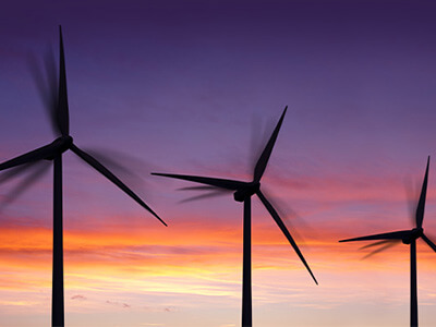 Várias turbinas eólicas em contraluz do pôr do sol
