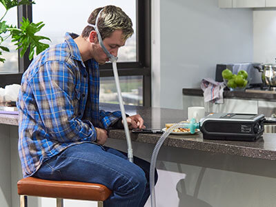 Paciente conectado a um dispositivo médico sentado a uma mesa de cozinha come qualquer coisa
